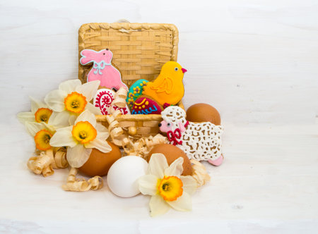 Easter cookie in a basket of flower Narcissus and chicken egg on wooden background