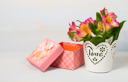 Decorative gift box and pot with flowers on wooden background.の写真素材