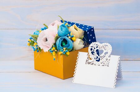 decorative flowers in a gift box with a card for text on wooden backgroundの写真素材