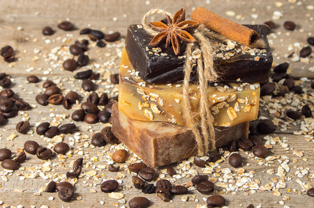 Handmade soap with coffee beans, oatmeal,cinnamon and anise star on a wooden background. Soft focus.の写真素材