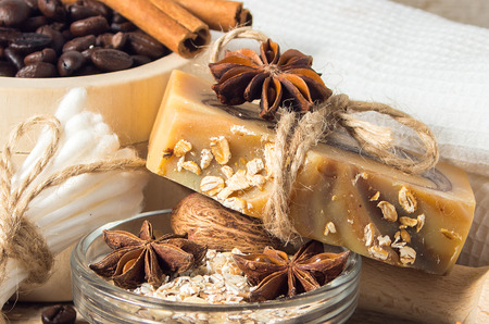 Handmade soap with coffee beans, oatmeal,cinnamon and anise star on a wooden background. Soft focus.の写真素材