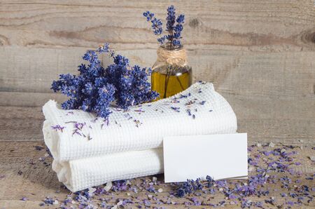 Spa concept. Lavender oil, lavender flowers and bath white towels on wooden background.の写真素材
