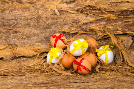 Easter concept. Easter eggs white and brown color with yellow and red bows on the tree bark