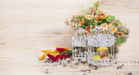 Easter still life. Bird cage with quail eggs and spring flowers on a wooden backgroundの写真素材