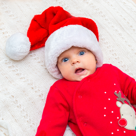  Little baby girl in santa hat looks at camera.の写真素材
