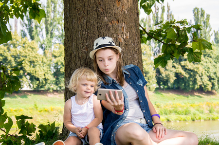 two happy sisters do selfie in the nature of a treeの写真素材
