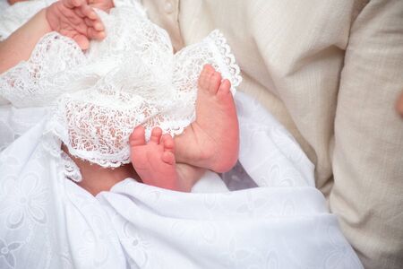 legs little newborn baby girl  in the parent hands on a white background clothes の写真素材