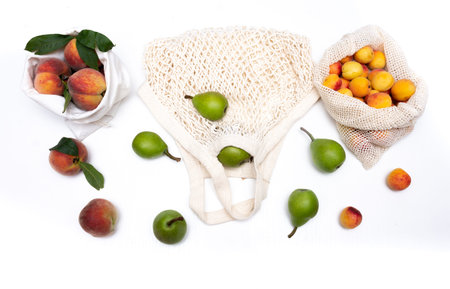 Fruits pears, peaches, apricots, pears in eco bags on a white background. Zero waste concept.