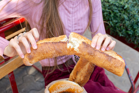fresh broken baguette in female hands