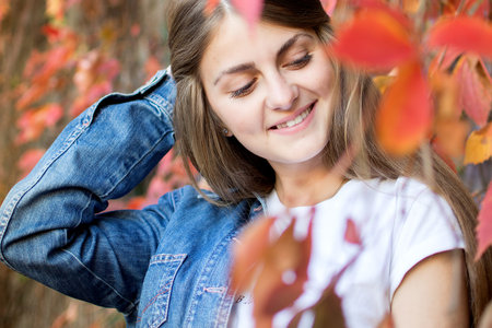 young girl with brown eyes smiling on a background of autumn leaves