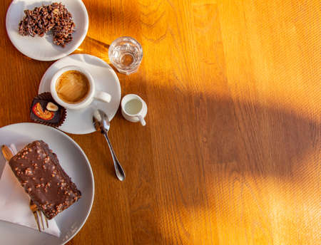 cup of espresso with cream and chocolate candy, cake, cookies on a wooden table. Cafe concept.の写真素材