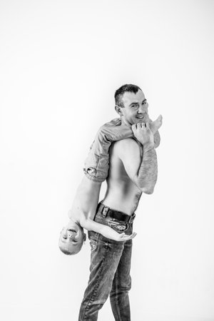 father playing with son. boy laughing happily riding on dad's back. black and white photoの写真素材