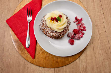 sweet eclair shu dessert with custard with pomegranate syrup and raspberries on a wooden table. cafe conceptの写真素材