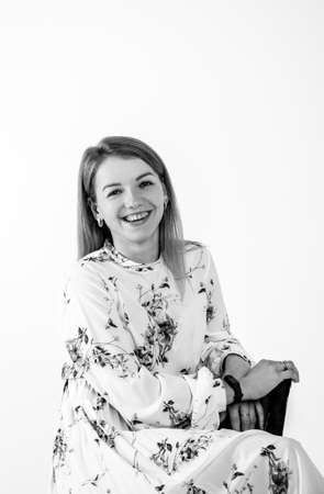 portrait of a beautiful young woman leaning on a chair. shooting studio on a gray backgroundの写真素材
