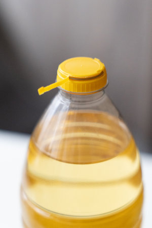 Yellow plastic cap for PET bottle with sunflower oil. New design with less plastic, the cap remains attached to the bottle after opening. Designed to reduce plastic waste.の写真素材