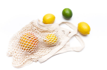 Citrus fruits in a white eco bag on a white background. Shopping for healthy food lemon, orange,...