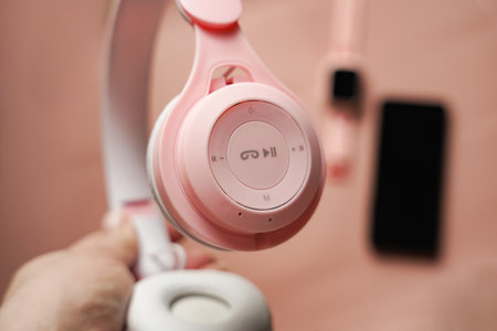 Close-up of a female hand holding a pink wireless headphones.の写真素材