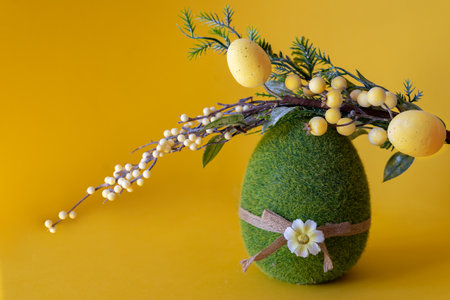 Easter composition on a yellow background. Green Easter egg and a branch with Easter eggs with space for text.の写真素材