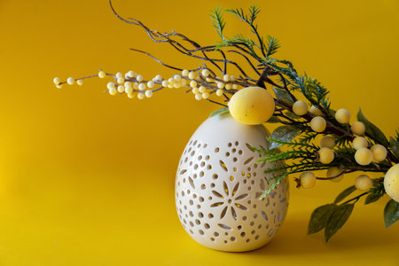 Easter white egg with branch and with Easter eggs on yellow background. Happy Easter with place for text.の写真素材
