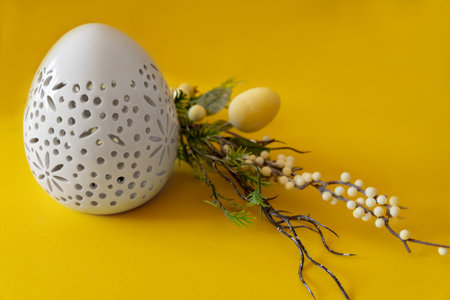 Easter white egg with branch and with Easter eggs on yellow background. Happy Easter with place for text.の写真素材