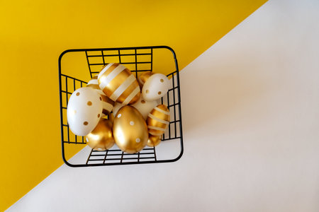 Easter concept. Easter eggs in a basket on a yellow and white background with space for text.の写真素材