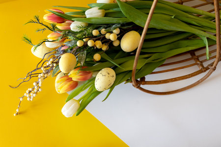 Bouquet of tulips and Easter eggs on a yellow and white background with space for text. Gift card.の写真素材