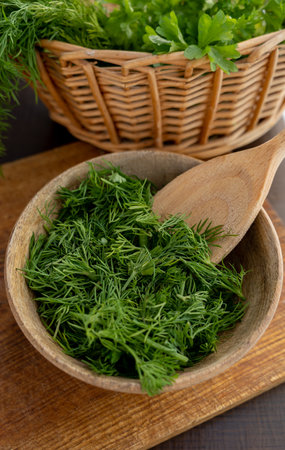 Chopped fresh dill in a wooden plate and wooden spoon. Preparing for freezing. Concept of aromatic herbs for cooking.の写真素材