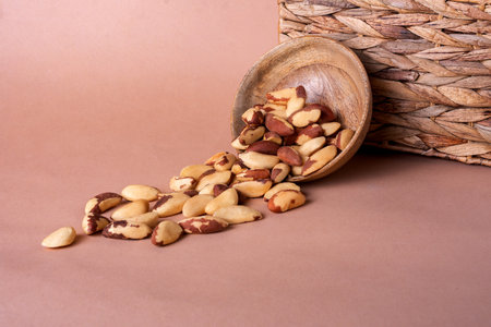 Brazil nuts in a wooden bowl on a beige mocha background with space for text. Tasty and healthy food. Shelled Brazil nuts close up.の写真素材