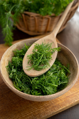 Chopped fresh dill with wooden spoon in a plate with chopped dill. Concept of aromatic herbs for cooking.の写真素材