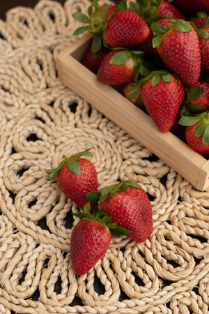 Several pieces of ripe strawberries next to a wooden box filled with berries. Dietary food. Fresh seasonal berries.の写真素材