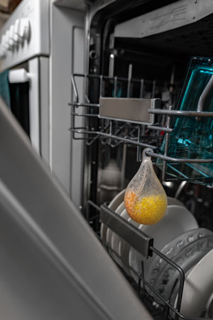 Dishwasher freshener hanging in an open dishwasher with washed dishes. Keeping the kitchen clean. Eco-friendly dishwashing detergent.の写真素材