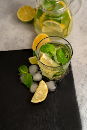 Iced tea with lemon, lime, mint and ice in a transparent glass on a slate board. Refreshing summer drink. Top view.の写真素材