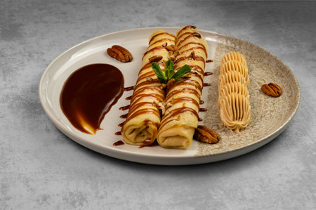 Dessert with pancakes with chocolate glaze and nut paste on a gray background. Cooking and baking.