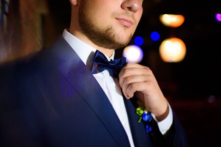 Groom holding his bow tie with his hands blue blackの写真素材