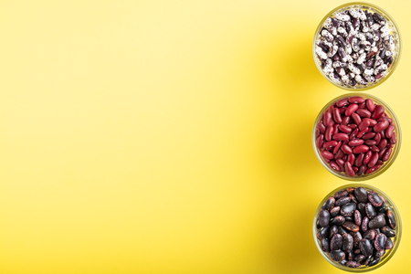 Colored bean in glass jars on a yellow background. Image with copy space.の写真素材