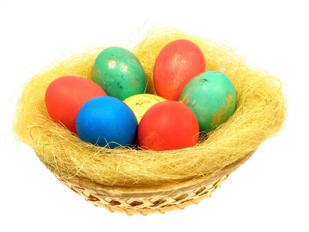 Colored eggs in a wicker basket from vines within the strawの写真素材