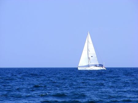Sailing yacht with triangular sails of white sails on the waves of the sea on the horizonの写真素材