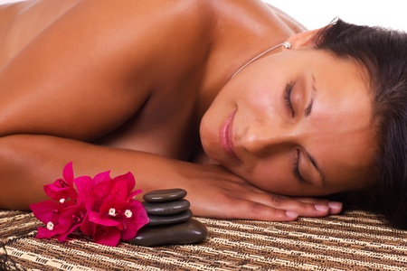 women in spa with spa stones with flowersの写真素材