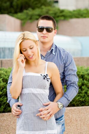 man embraces a girl while she talks on the phoneの写真素材