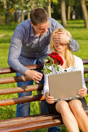boyfriend with flowers covering female eyes to surprise herの写真素材