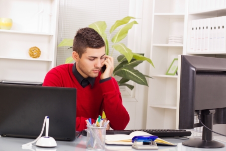 Handsome young business man at office talking on phoneの写真素材