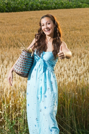 beautiful smiling woman in a long blue dress posing in wheat fieldの写真素材