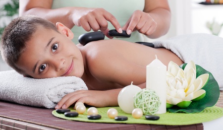 therapist massaging a young boy in the spa salonの写真素材