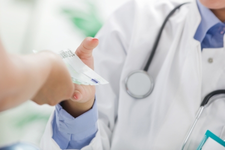 female doctor receiving money from a patientの写真素材