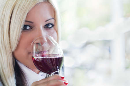 blonde young woman drinking red wineの写真素材