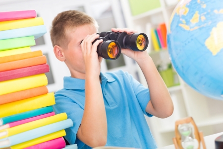 Blonde boy using binoculars while studyingの写真素材