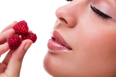 Beautiful woman eating sweet raspberriesの写真素材