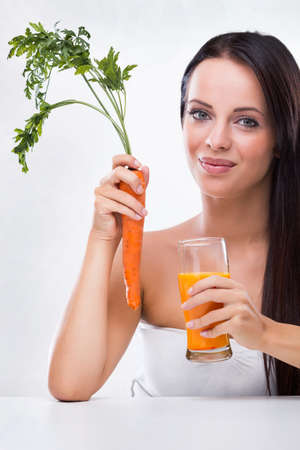 Beautiful young woman holding carrot and carrot juiceの写真素材