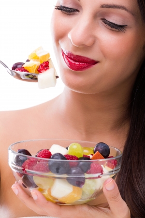 Beautiful woman eating fresh fruit saladの写真素材