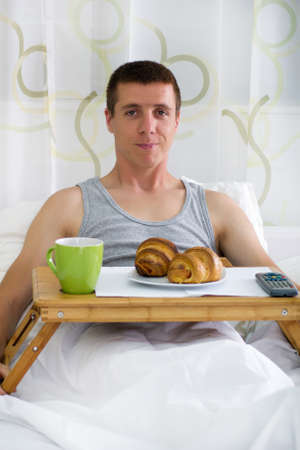 photo of man having breakfast in the bed の写真素材